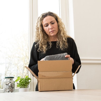 Eine Frau packt ein Kleidungsstück aus einem Paket aus.