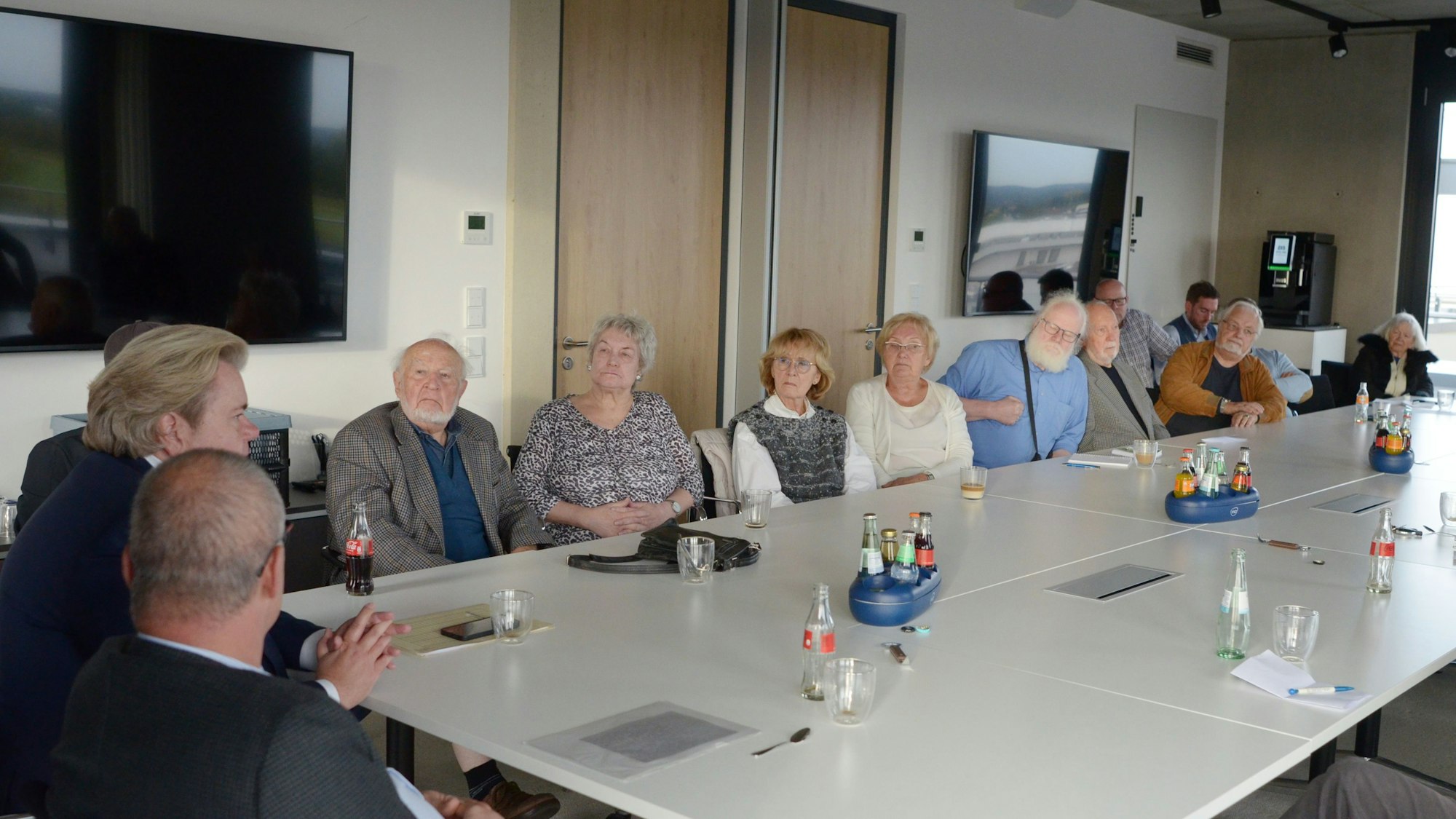 In einem Versammlungsraum sitzen die Teilnehmerinnen und Teilnehmer einer Diskussion mit David Klapheck, dem Geschäftsführer der Synagogengemeinde Köln.