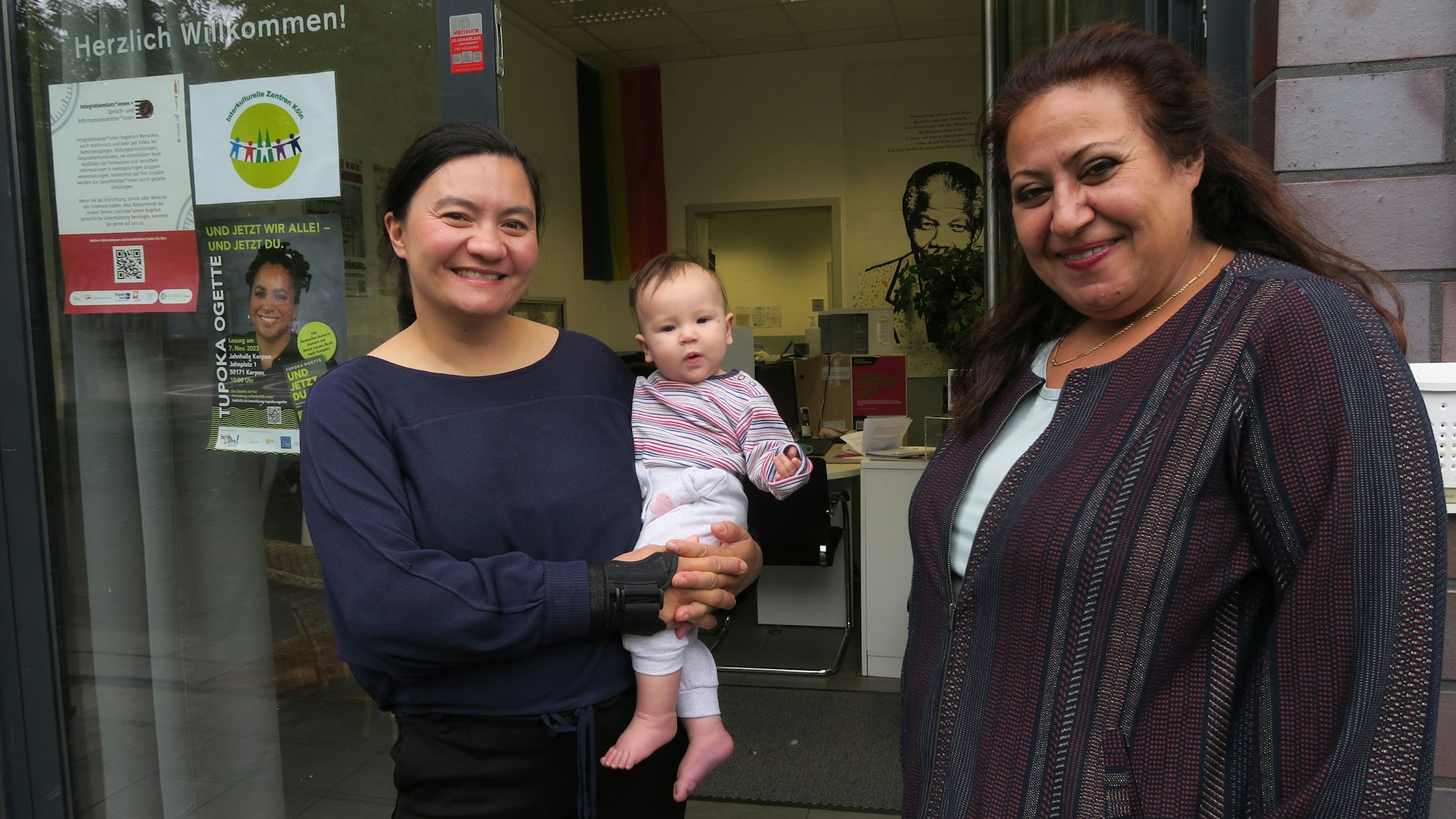 Zwei Frauen stehen vor dem Eingang des Integratinshauses in Kalk, eine von ihnen hat ein Baby auf dem Arm.