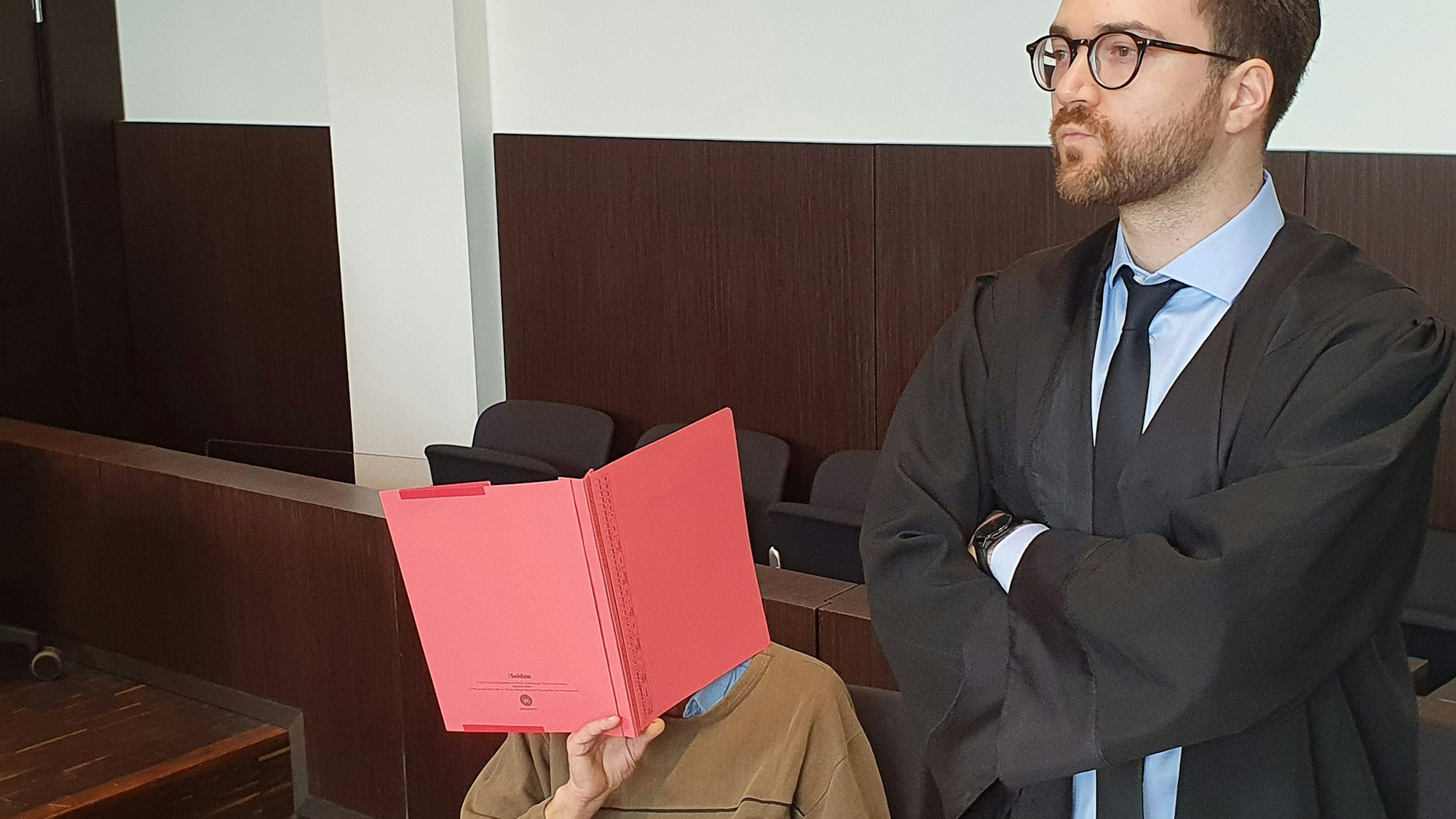 Der Angeklagte (l) sitzt neben seinem Verteidiger Maximilian Klefenz im Verhandlungssaal am Düsseldorfer Landgericht und verdeckt sein Gesicht.