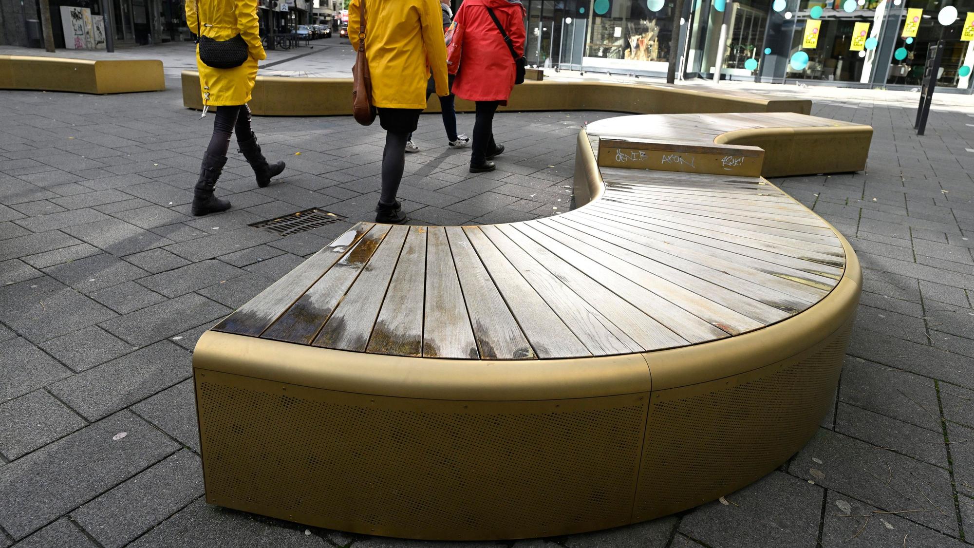 Wuppertal: Passanten gehen an den goldglänzenden Bänken in der Fussgängerzone von Elberfeld vorbei.