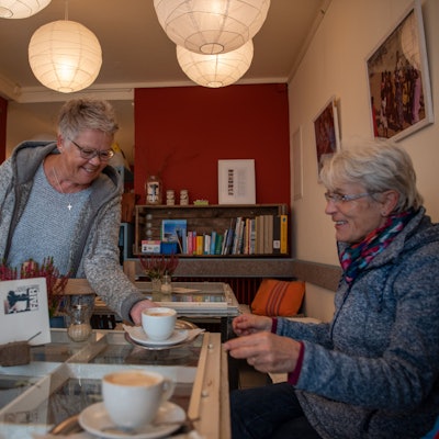 Monika Geißler serviert im Fair-Café in Zülpich einer Besucherin eine Tasse Kaffee.