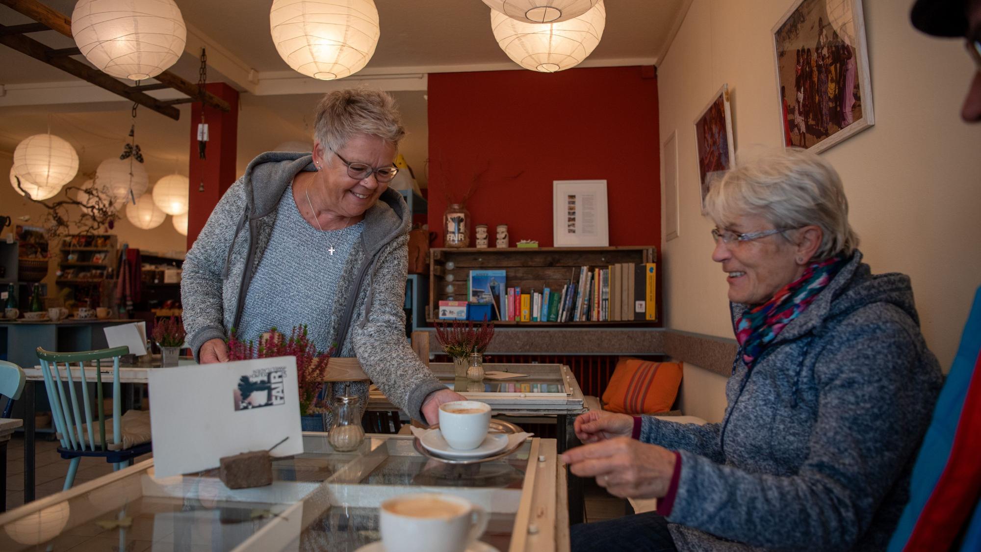 Monika Geißler serviert im Fair-Café in Zülpich einer Besucherin eine Tasse Kaffee.