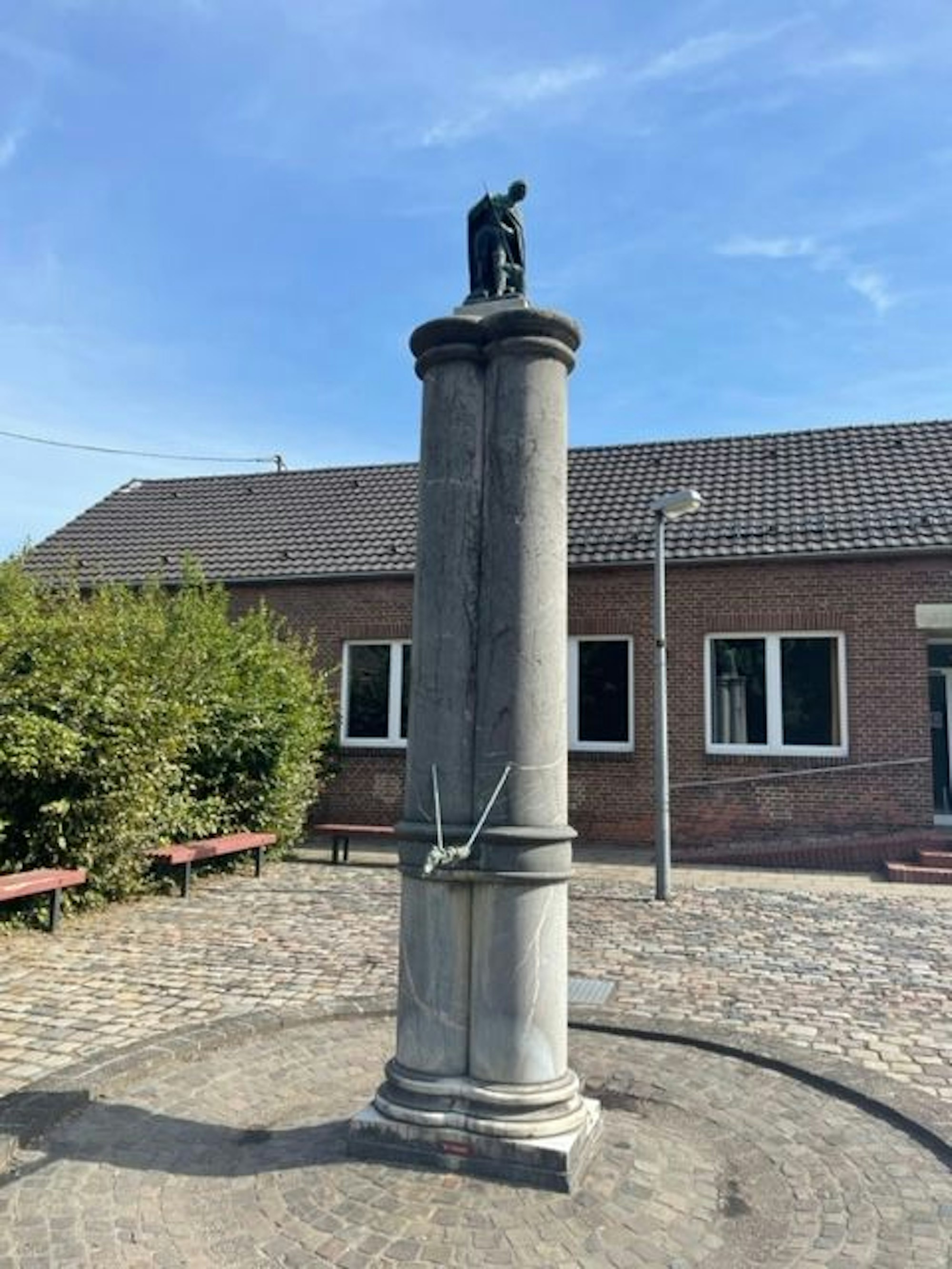 Ein hoher Brunnen steht auf einem Platz.