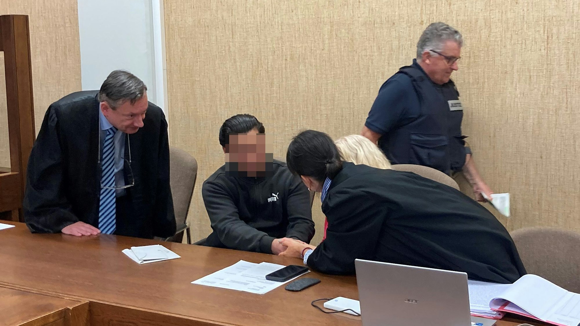 Das Bild zeigt den Angeklagten im Gespräch mit seinen Anwälten.