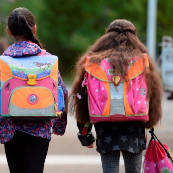 Drei Schülerinnen laufen mit ihren Schulranzen zur Schule. Die Gesichter der Kinder sind weg von der Kamera gewandt. (Archivbild)