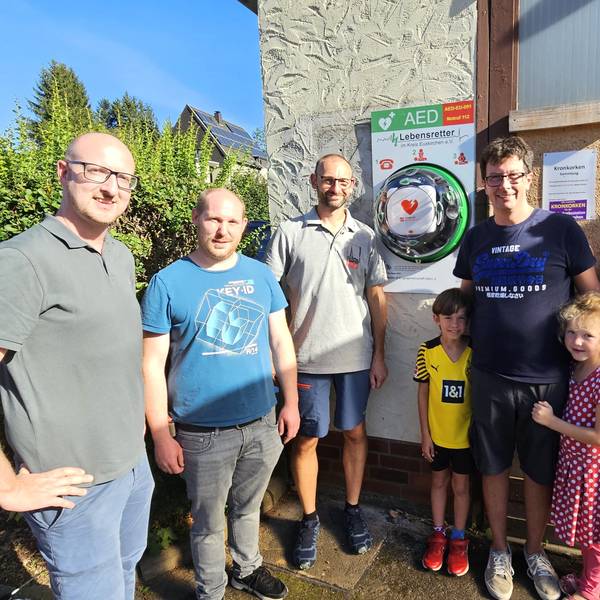 Um den Defibrillator stehen von links Ingo Pfennings, Christian Larres, Stefan Groß, Jesko Priewe mit Tochter und Sohn sowie Oliver Müller.