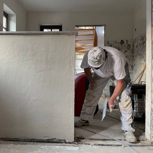 Ein Handwerker bearbeitet eine Wand mit einer Kelle.