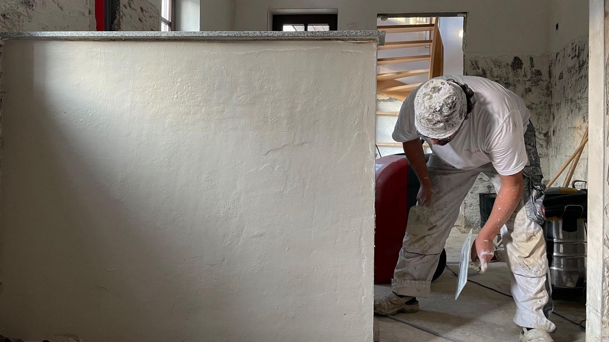 Ein Handwerker bearbeitet eine Wand mit einer Kelle.