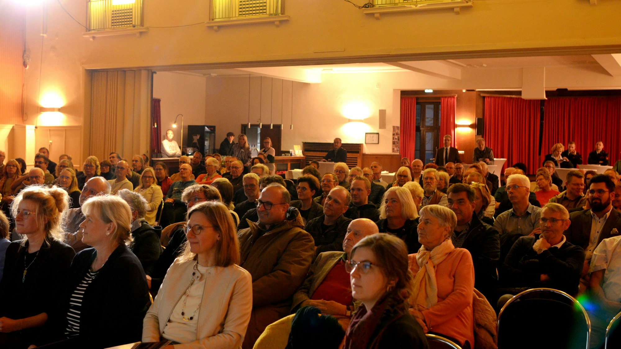Die Sitzreihen im Euskirchener Casino, einer Veranstaltungsstätte, sind zur Ausstellungseröffnung dicht besetzt.