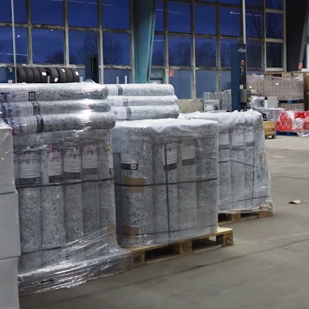 Paletten mit Baustoffen stehen in einer Halle.