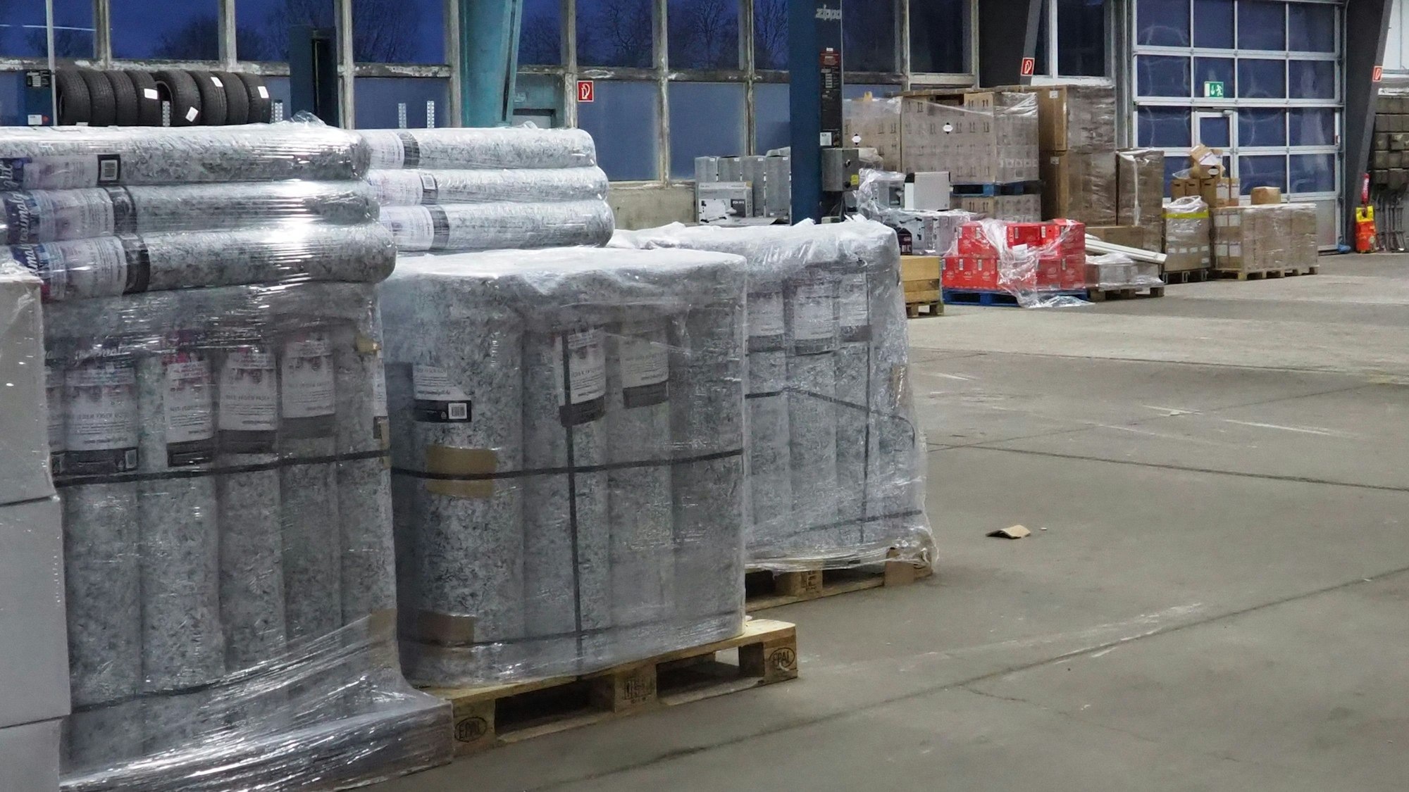 Paletten mit Baustoffen stehen in einer Halle.