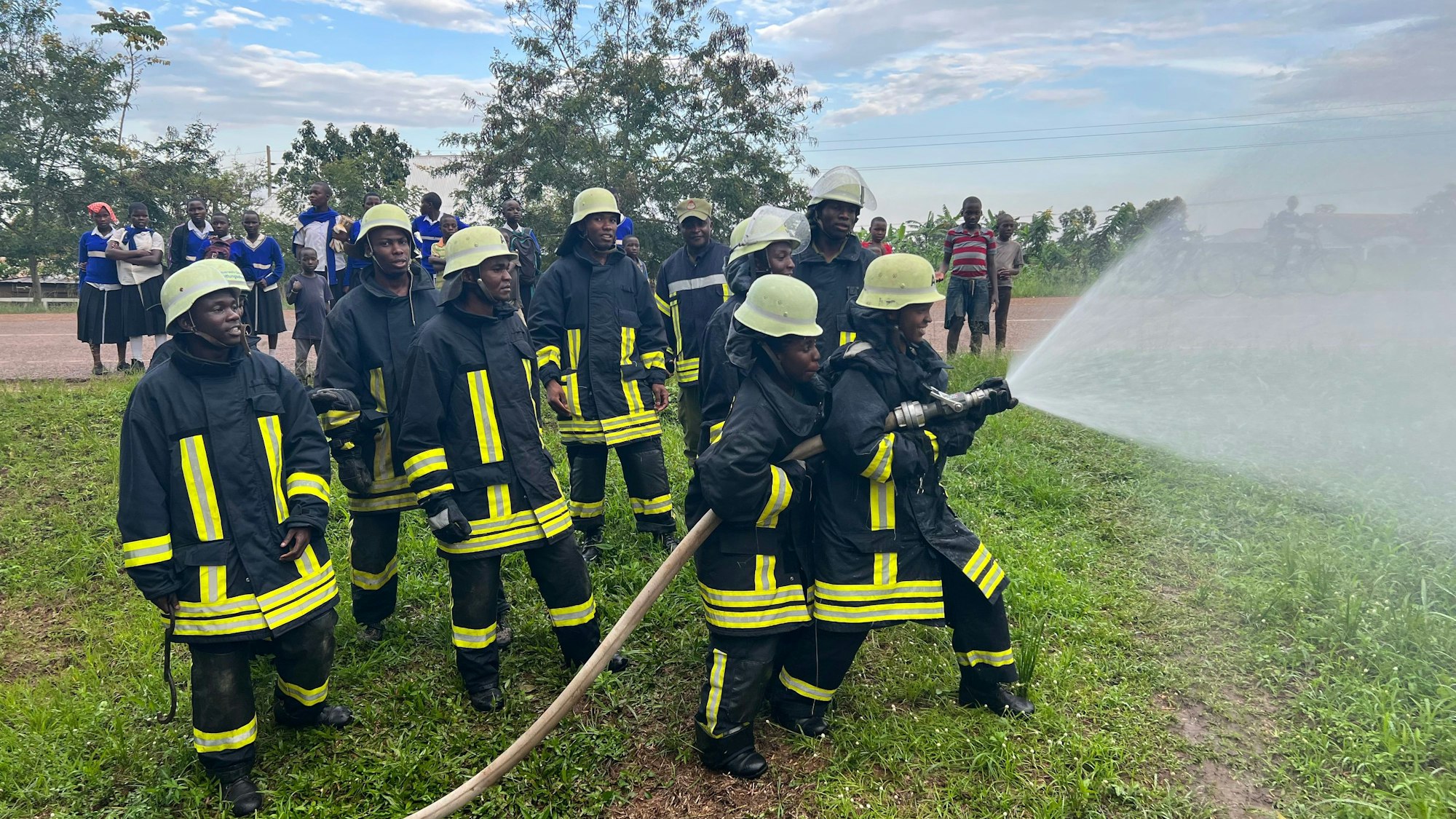 Eine Gruppe von Feuerwehrleuten sprüht Wasser aus einem Feuerwehrschlauch.