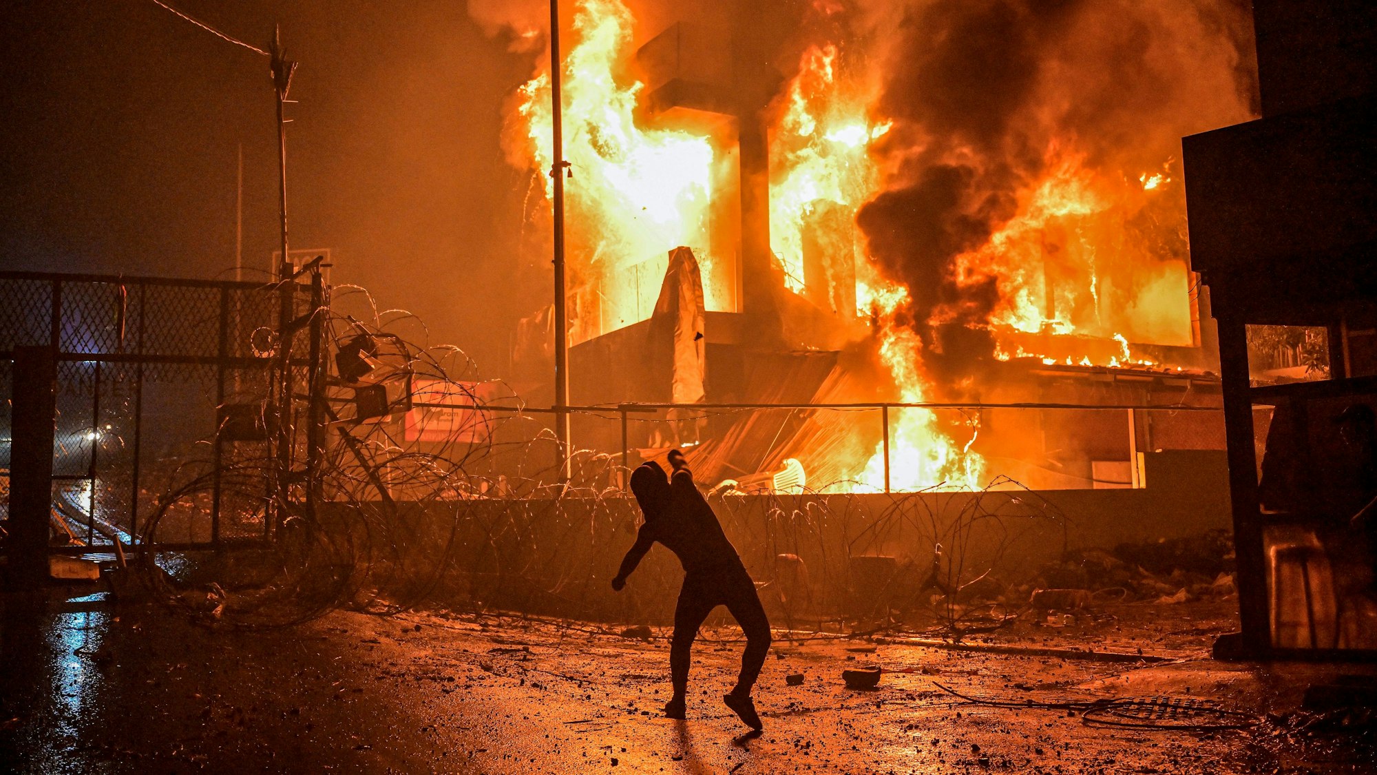 Ein libanesischer Demonstrant wirft Steine auf ein brennendes Gebäude in der Nähe der US-Botschaft während einer Solidaritätsdemonstration mit der Bevölkerung des Gazastreifens.