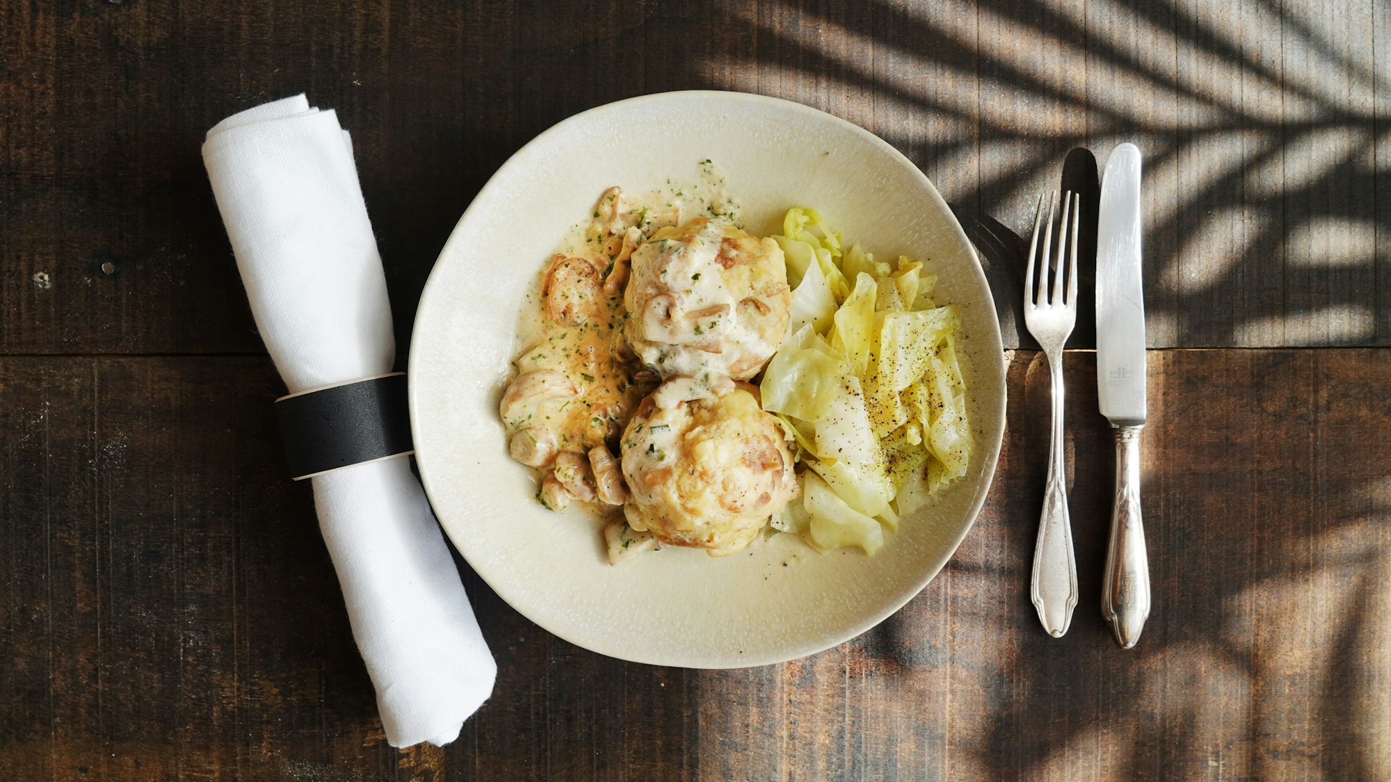 Die Knödel mit der Soße und dem Spitzkohl sind auf einem Teller angerichtet.