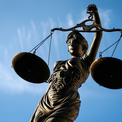 Eine Statue der Justitia hält eine Waage in ihrer Hand.