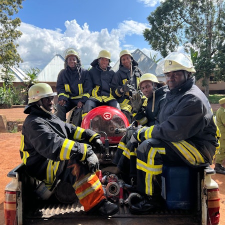 Foto von sechs Feuerwehrmännern mit Gerätschaften auf der Ladefläche eines Pick-ups.