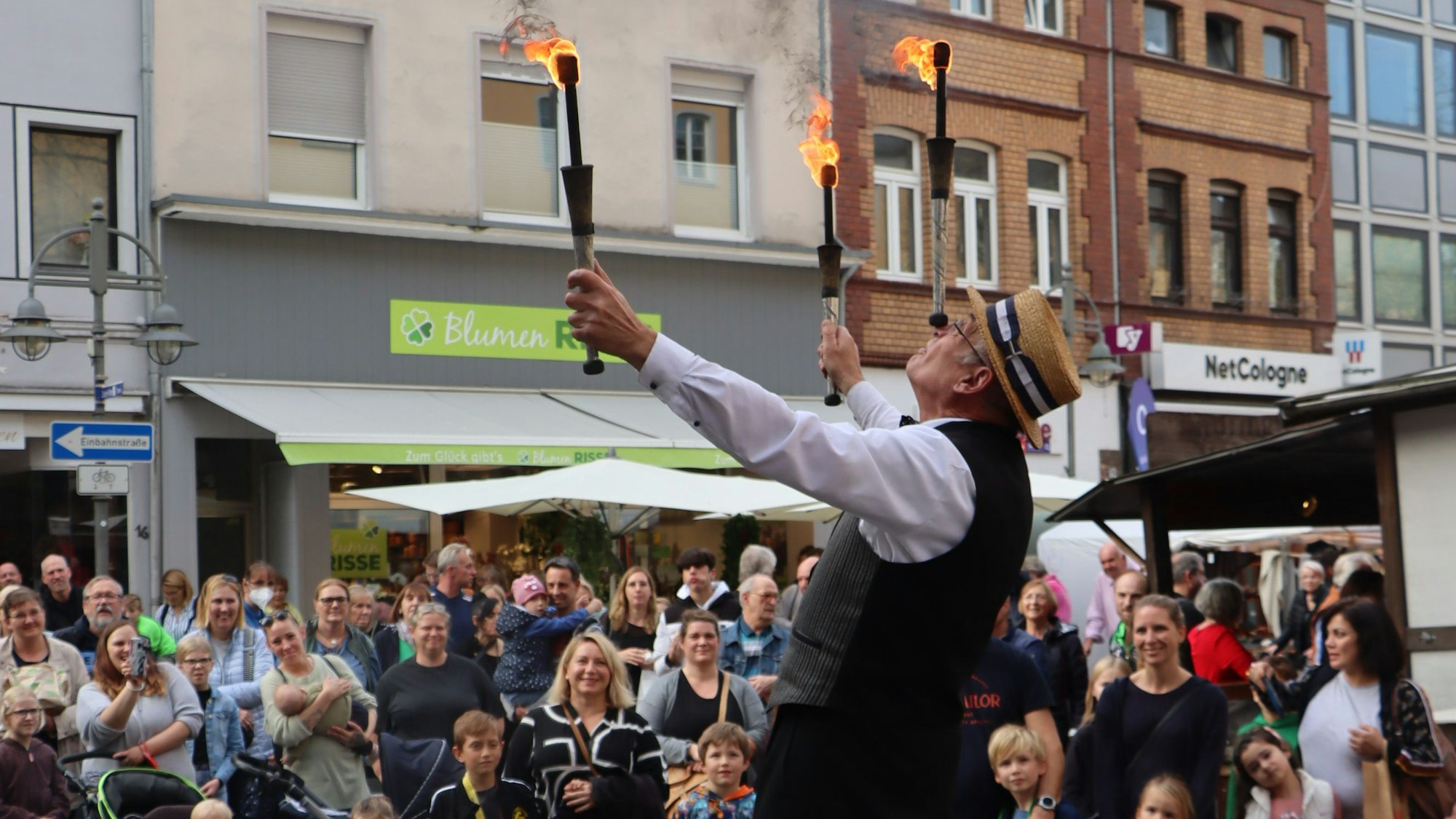 Zu sehen ist ein Gaukler, der vor großem Publikum mit Fackeln jongliert.