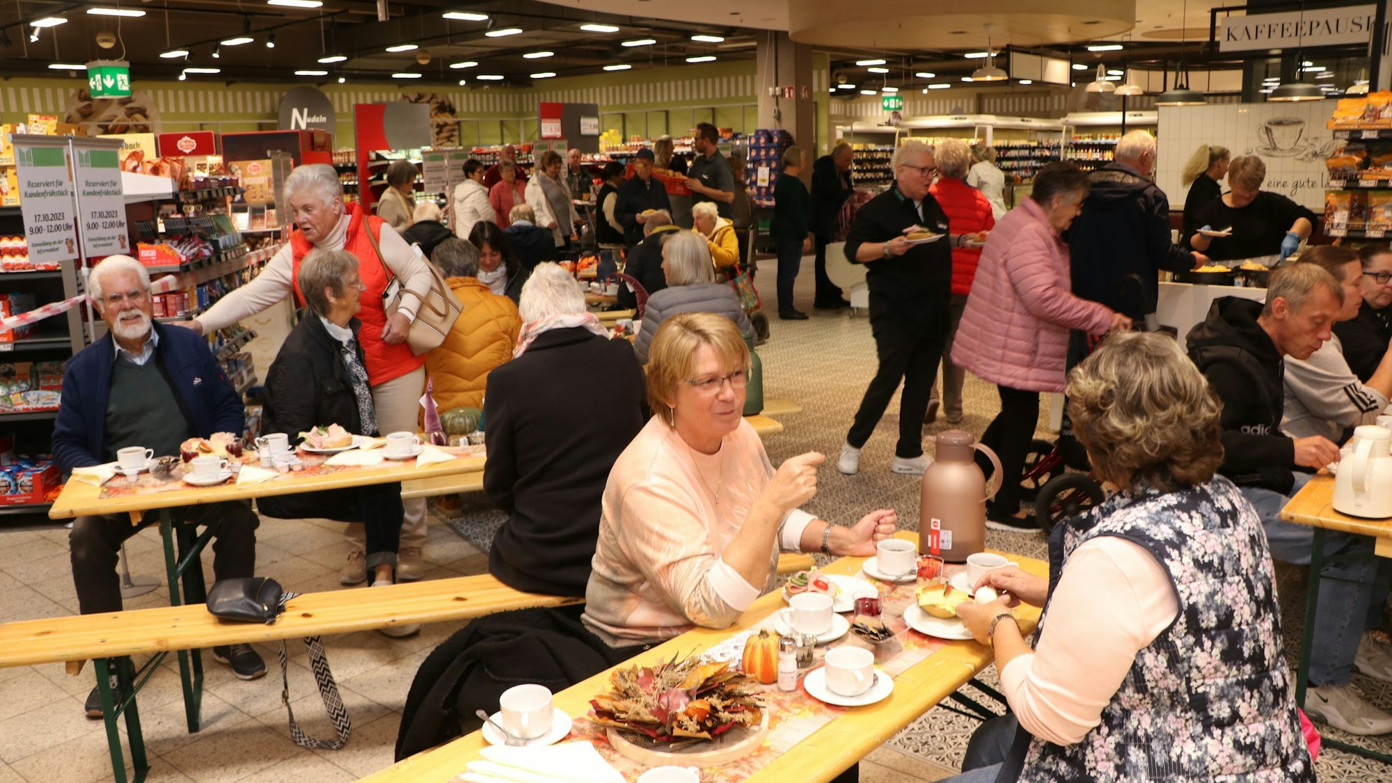 Auf dem Bild sind Frechener zu sehen, die an langen Bänken frühstücken.