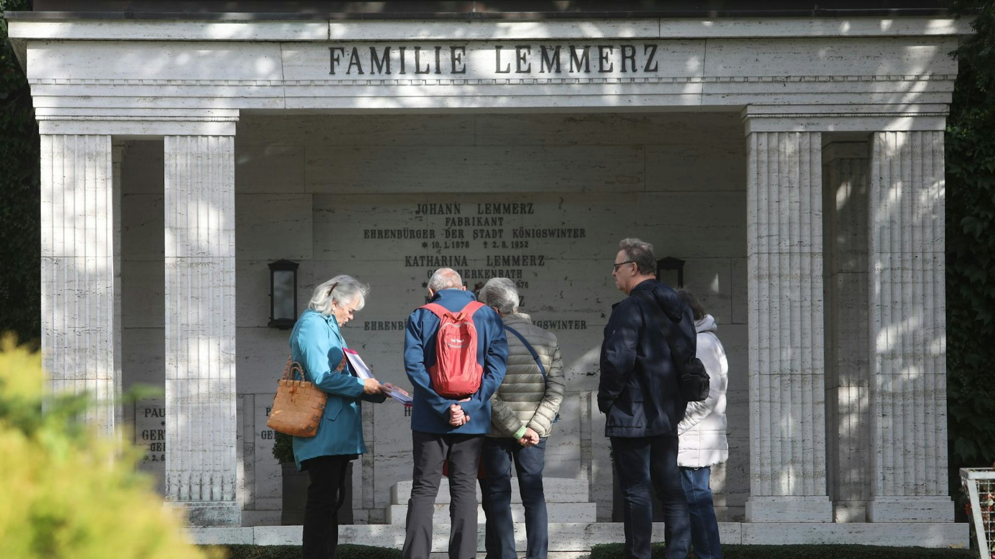 Eine Gruppe von Menschen stehen vor dem großen Familiengrab der Familie Lemmerz.