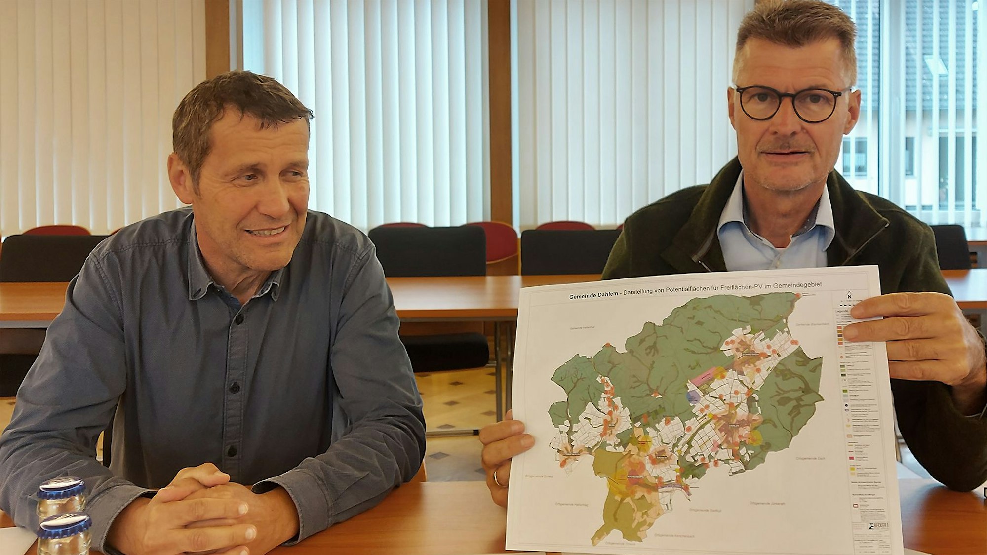 Dahlems Bürgermeister Jan Lembach (r.) hält eine Karte in der Hand. Neben ihm an einem Tisch sitzt sein Allgemeiner Vertreter Erwin Bungartz.