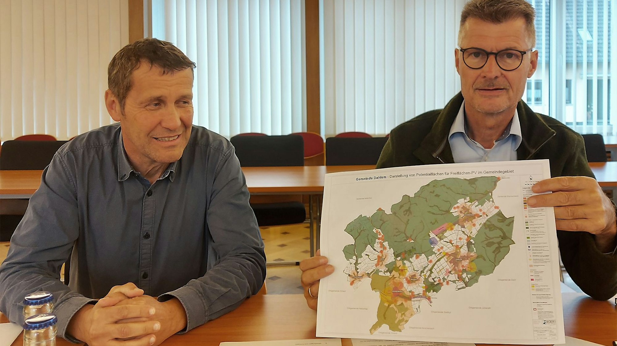 Jan Lembach zeigt eine Karte, die die Potenzialflächen für Freiflächen-Photovoltaik im Gemeindegebiet von Dahlem.