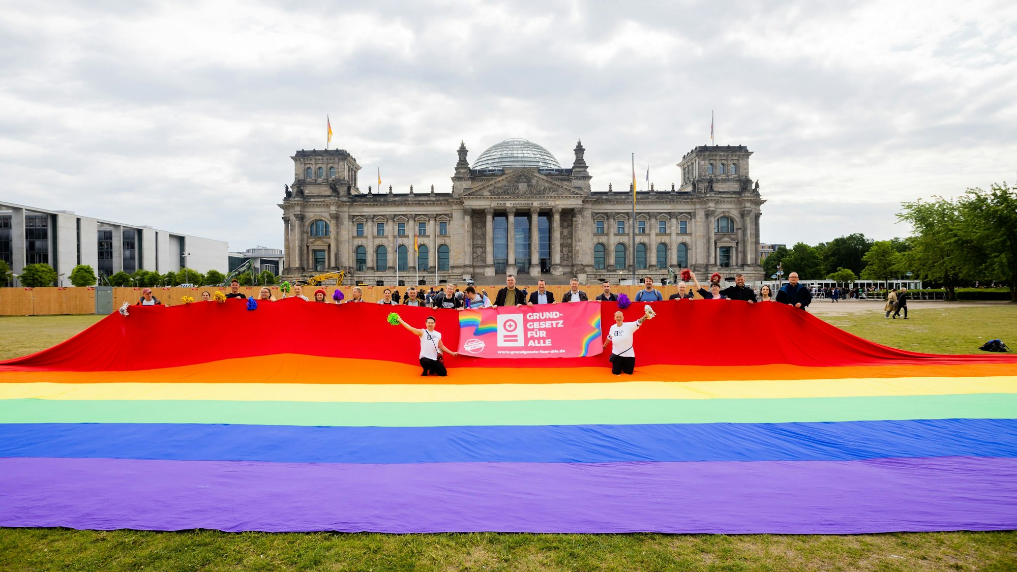 Teilnehmer einer Aktion der Initiative Grundgesetz für Alle für die Rechte und den verfassungsmäßigen Schutz der Rechte queerer Menschen halten vor dem Reichstagsgebäude eine Regenbogenfahne. Laut der Initiative handelt es sich um die flächenmäßig größte Regenbogenfahne Deutschlands.