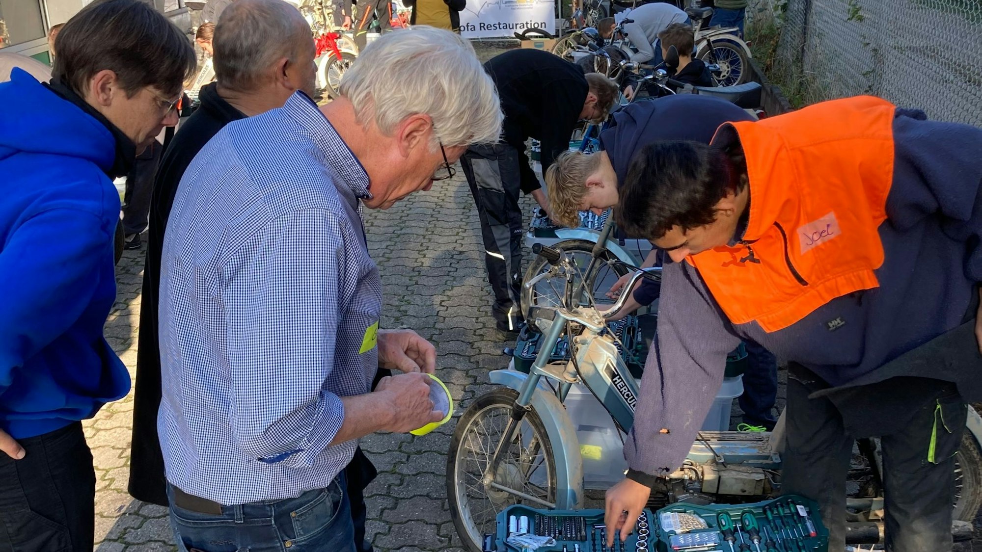 Schüler und Kfz-Meister Achim Heymann sehen sich einen Werkzeugkasten an.