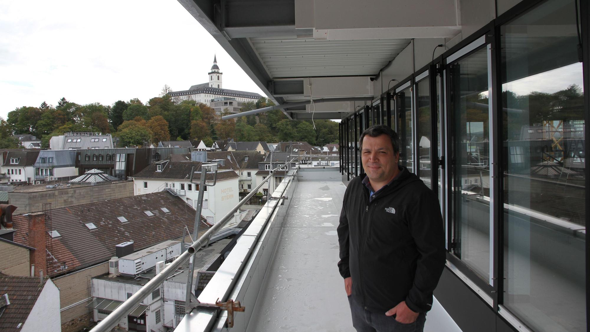 Ein Mann Weste steht auf dem Umlauf vor dem Staffelgeschoss des Rathauses in der fünften Etage, im Hintergrund ist der Michaelsberg zu sehen.