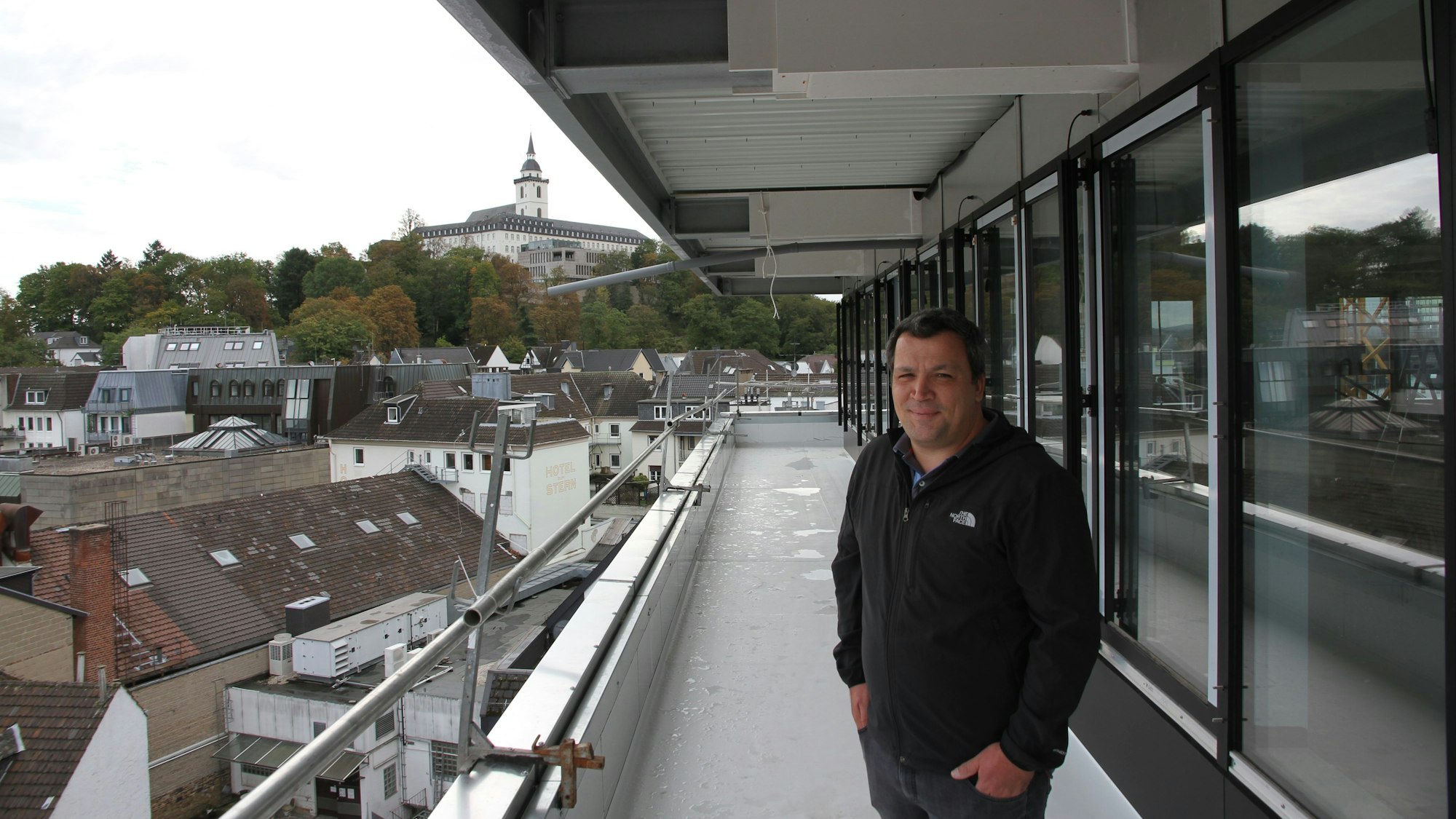 Ein Mann Weste steht auf dem Umlauf vor dem Staffelgeschoss des Rathauses in der fünften Etage, im Hintergrund ist der Michaelsberg zu sehen.