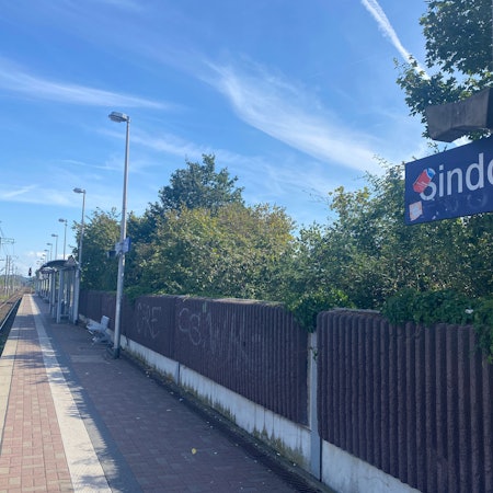 Die Bahnstation in Sindorf. An einer Schallschutzmauer ist Graffiti.