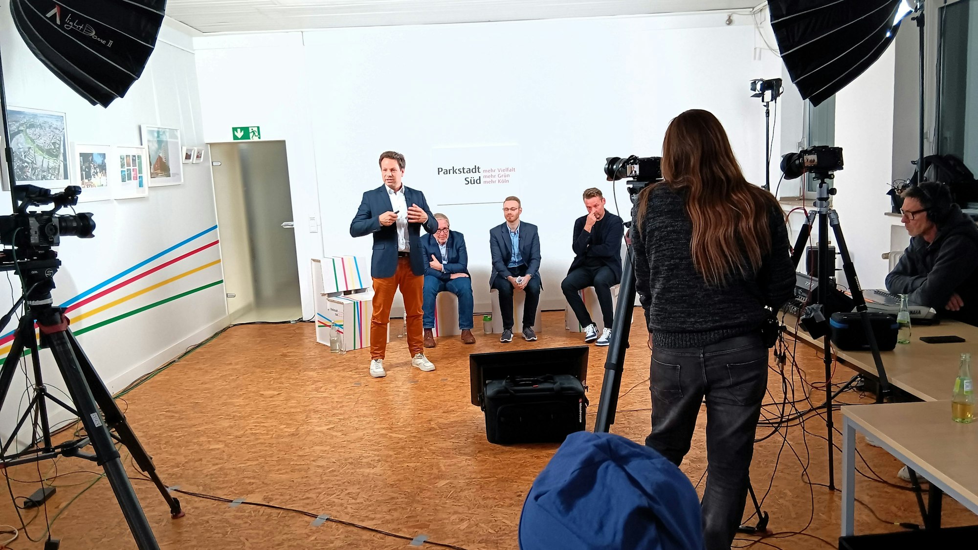 Menschen sitzen auf Hockern und werden gefilmt.