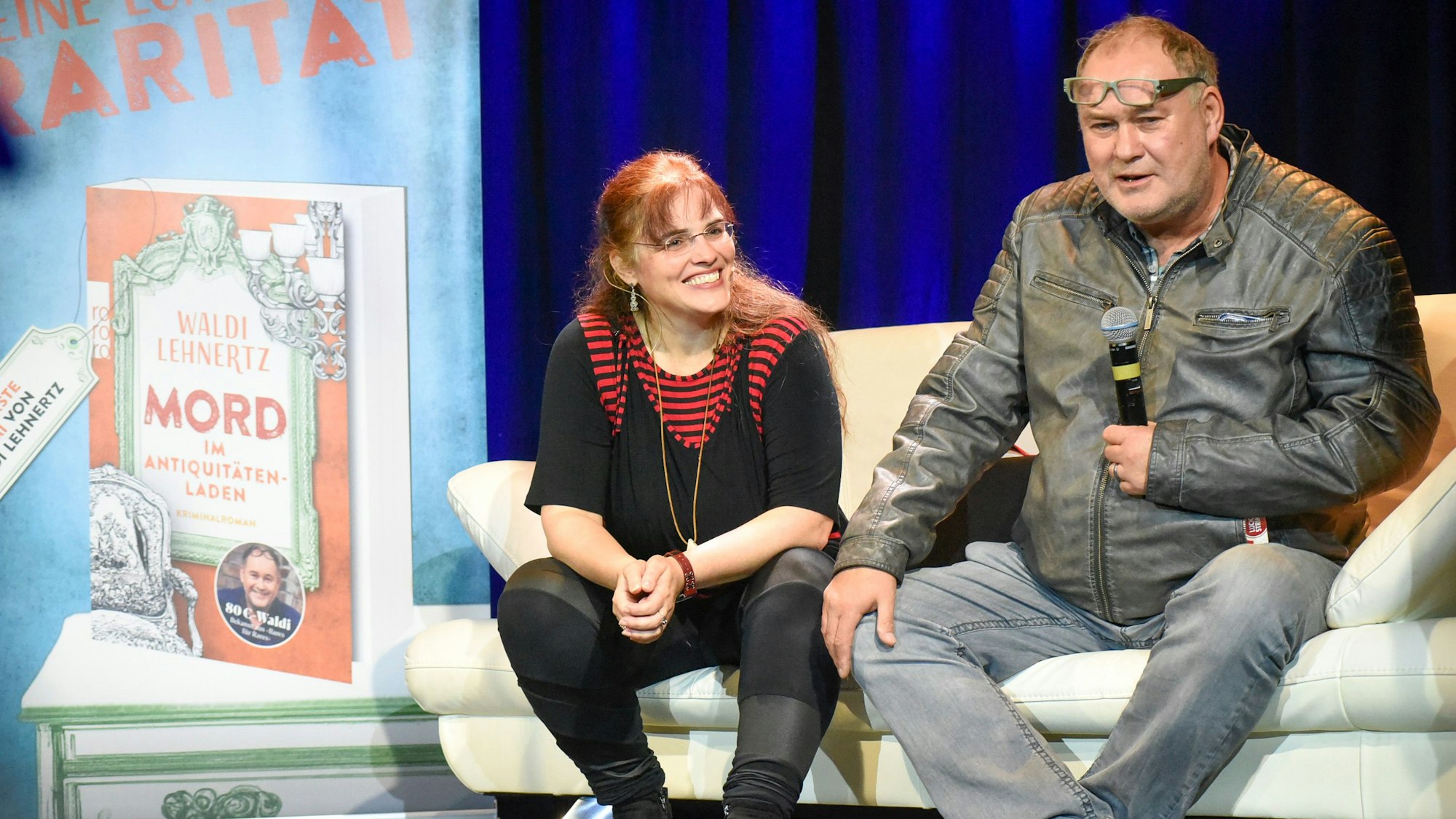 Der Autor und seine Co-Autorin sitzen auf einem Sofa und sprechen über ihr Buch.