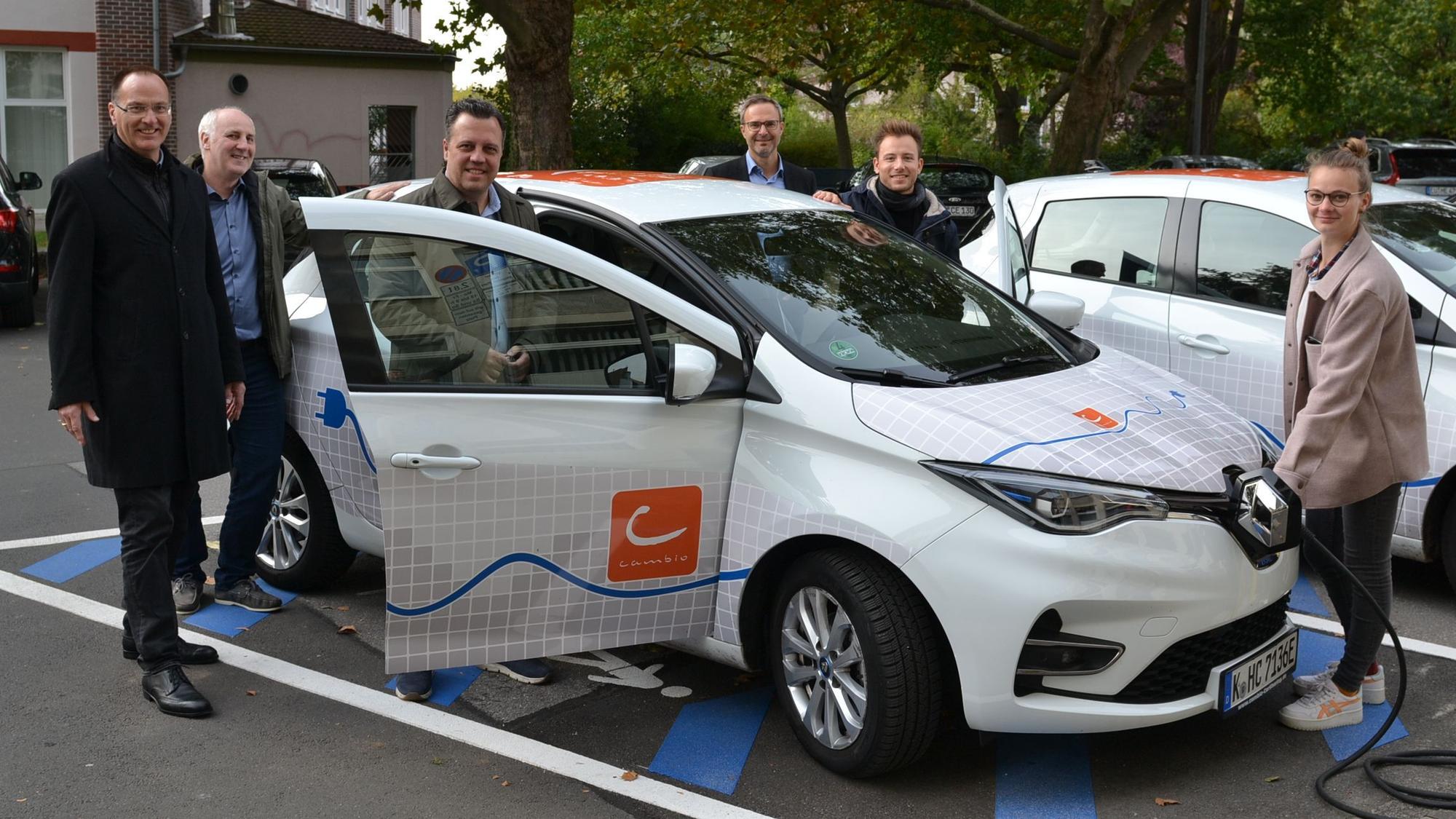 Sacha Reichelt und Vertreter des Kreises Euskirchen, der SVE, der e-regio und des Car-Sharing Anbieters Cambio präsentieren ein E-Auto des Typs Renault Zoe.