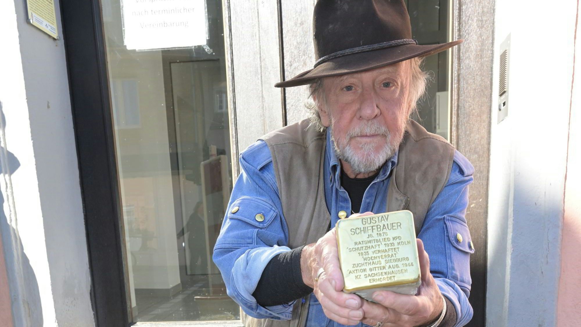 Das Foto zeigt Günter Demnig mit dem Stolperstein für Gunter Demnig.