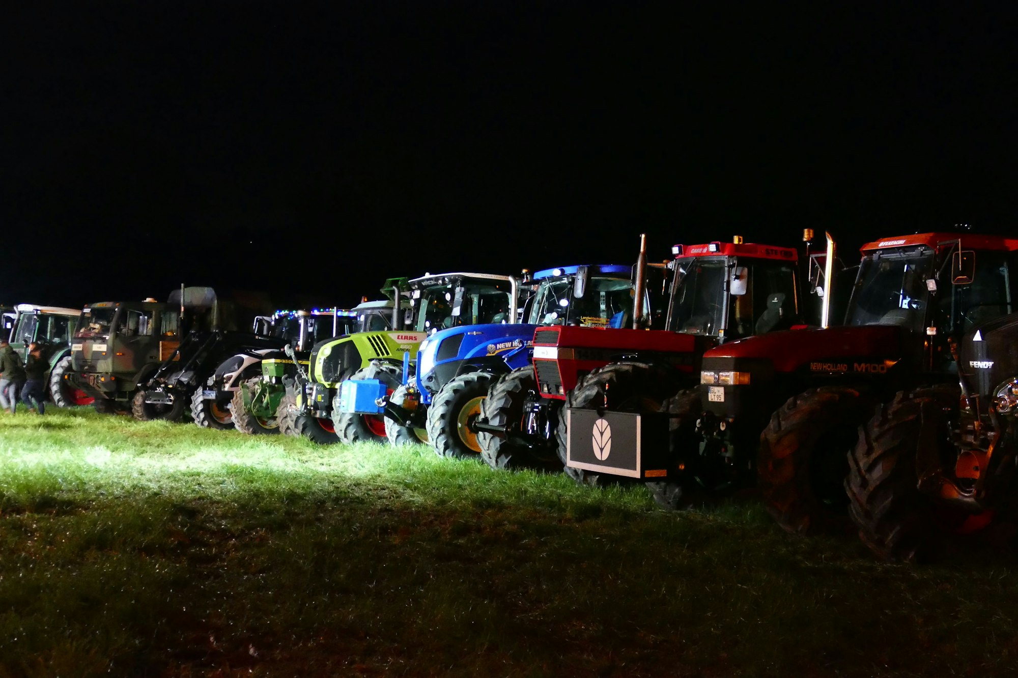 Mehrere Traktoren stehen nebeneinander auf einer Wiese
