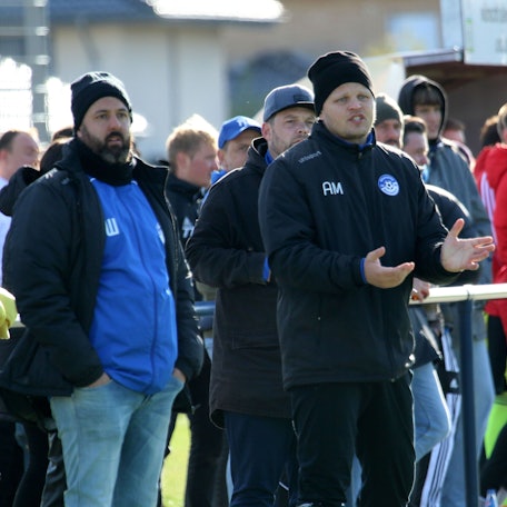 Beniamin Warrach und Artur Mezler, beide mit Mütze, schauen einer Spielszene zu.