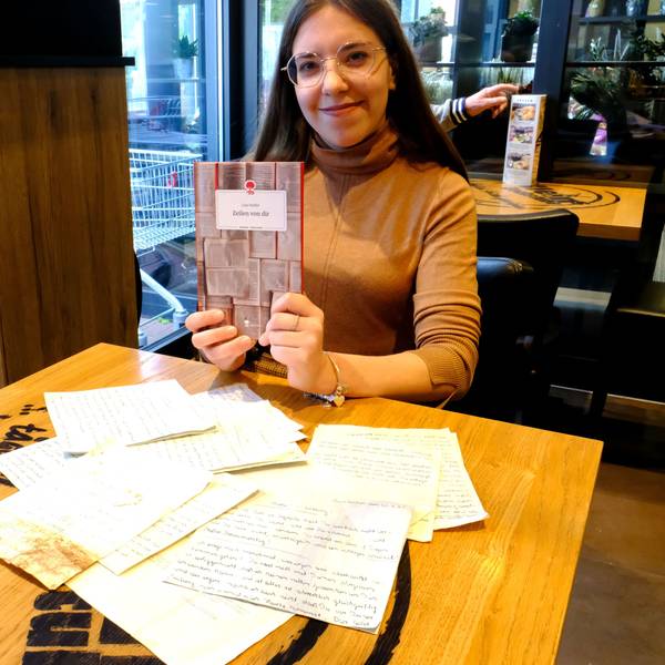 Lina Siedler aus Mechernich präsentiert das Buch über ihre Großeltern. Vor ihr auf dem Tisch liegen einige alte Briefe.
