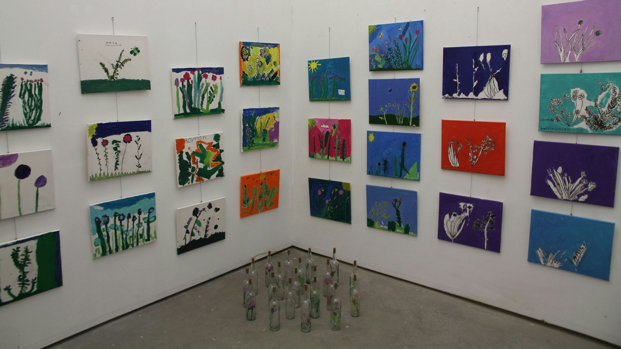 Gemalte Bilder mit Pflanzenteilen in einer Ecke der Ausstellung im Pumpwerk