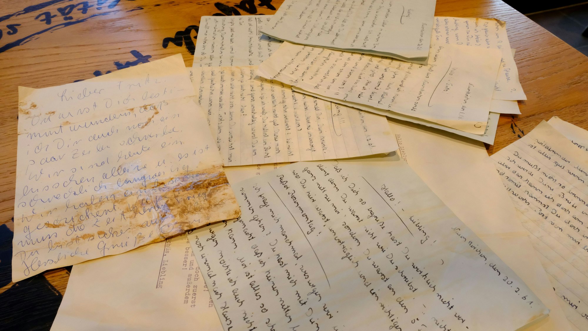 Mehrere alte Briefe liegen auf einem Tisch, einer ist mit Schlamm verschmutzt.