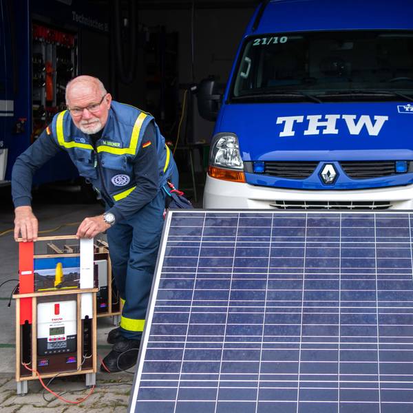 Das Bild zeigt den Entwickler neben einer mobilen Solarfläche. Zudem bedient er die Ladestation.