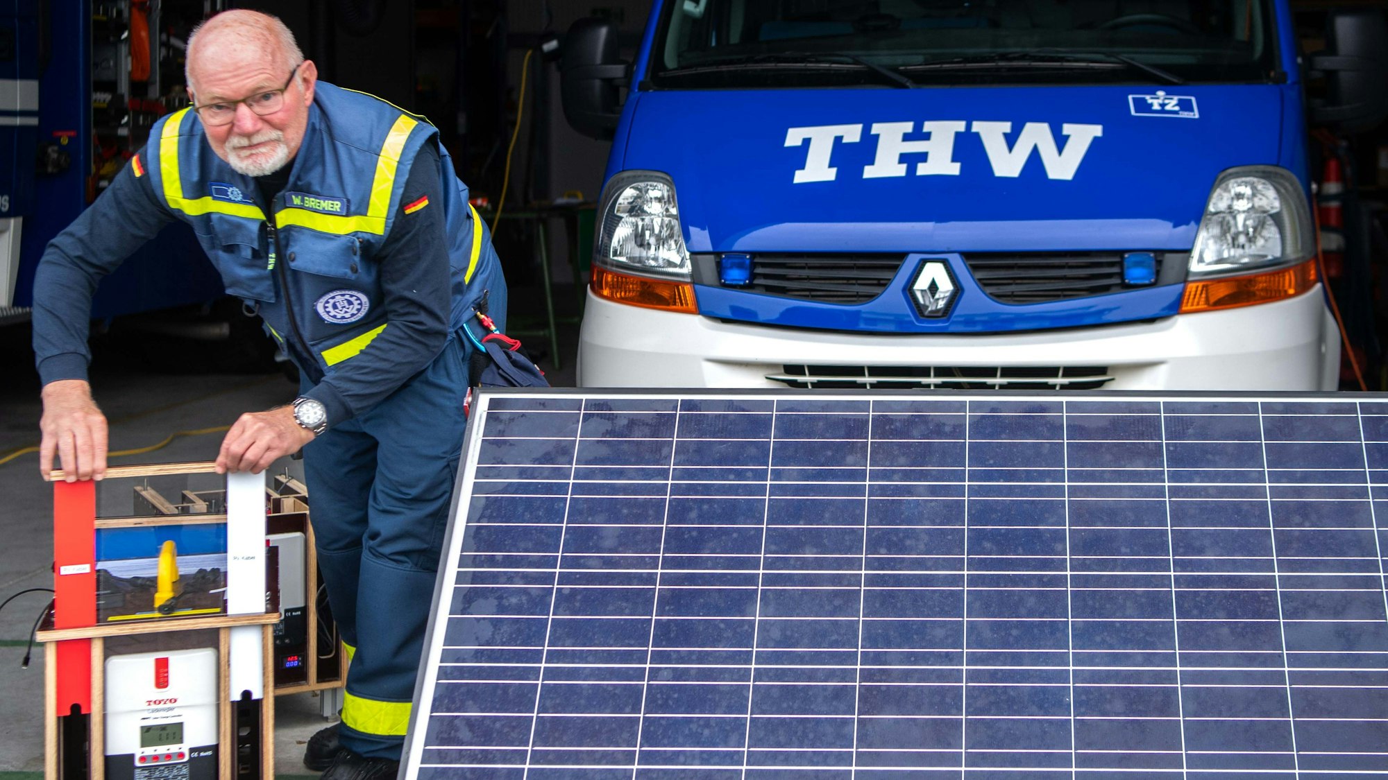 Das Bild zeigt den Entwickler neben einer mobilen Solarfläche. Zudem bedient er die Ladestation.