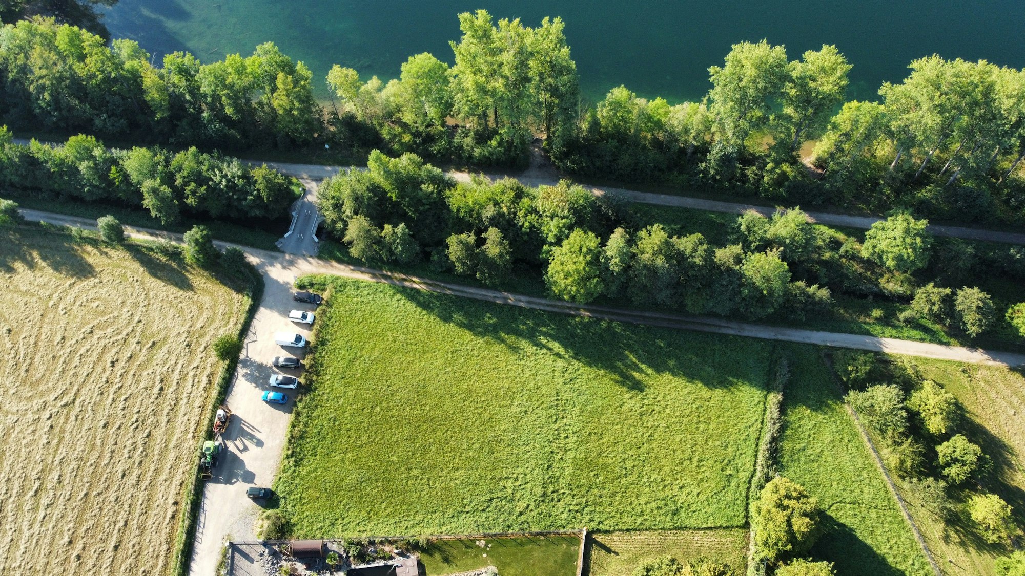 Eine Luftaufnahme zeigt eine Wiese, angrenzende Bäume und den Rand eines Sees.