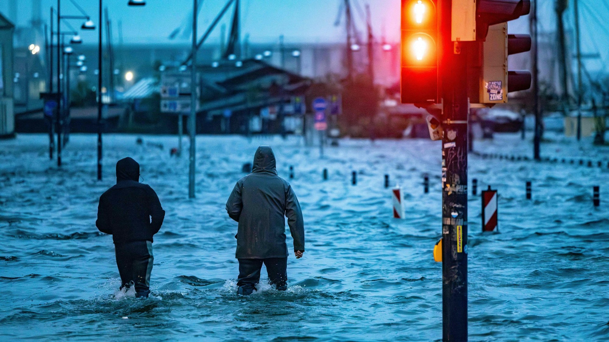 Menschen gehen durch die überfluteten Straßen in Flensburg.