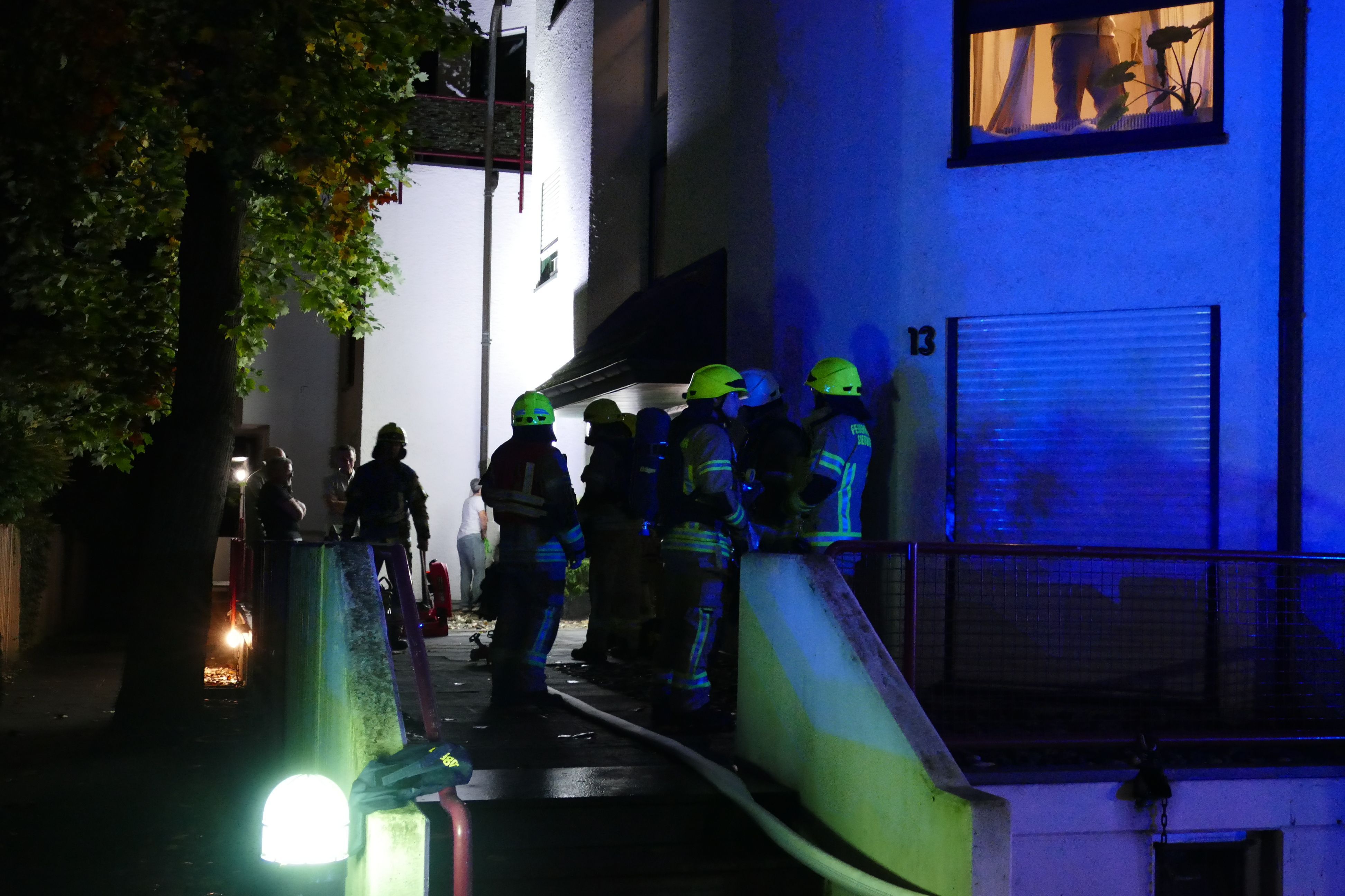 Feuerwehrleute stehen vor einem Wohnhaus.