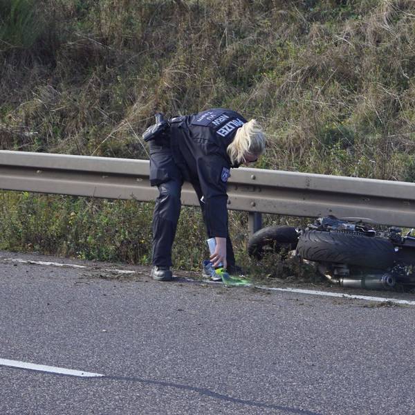 Eine Polizistin markiert Spuren nach einem Unfall, bei dem ein Motorradfahrer auf der B266 bei Mechernich-Firmenich ums Leben gekommen ist. Das Motorrad liegt an einer Leitplanke.