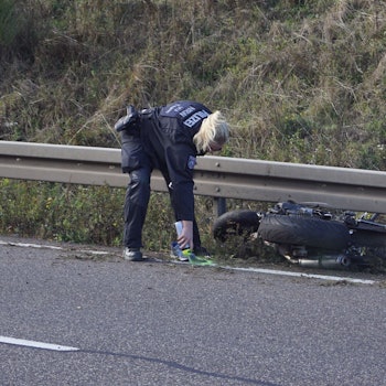Eine Polizistin markiert Spuren nach einem Unfall, bei dem ein Motorradfahrer auf der B266 bei Mechernich-Firmenich ums Leben gekommen ist. Das Motorrad liegt an einer Leitplanke.