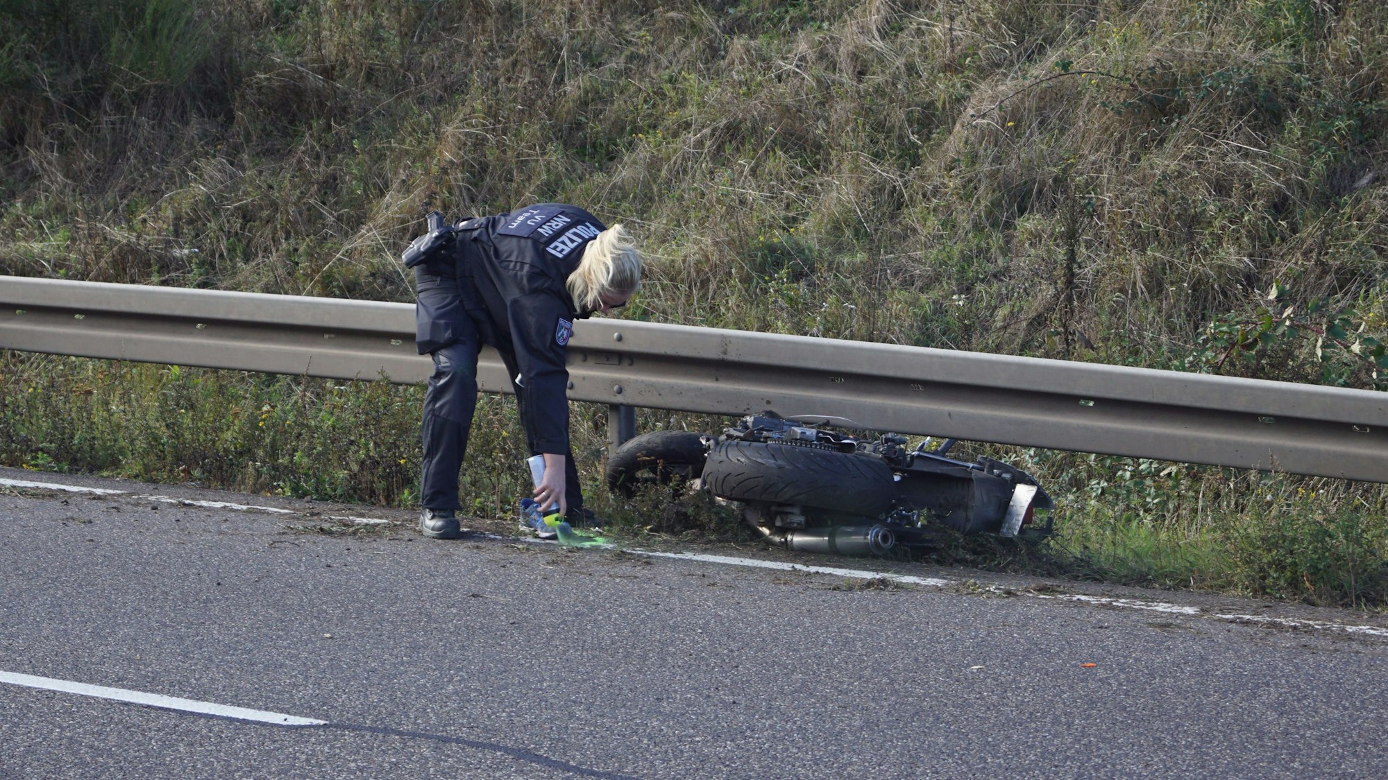 Das Bild vom Oktober 2023 zeigt eine Polizistin, die nach einem tödlichen Unfall auf der B266 eine Stelle an einem Motorrad mit Sprühfarbe markiert.