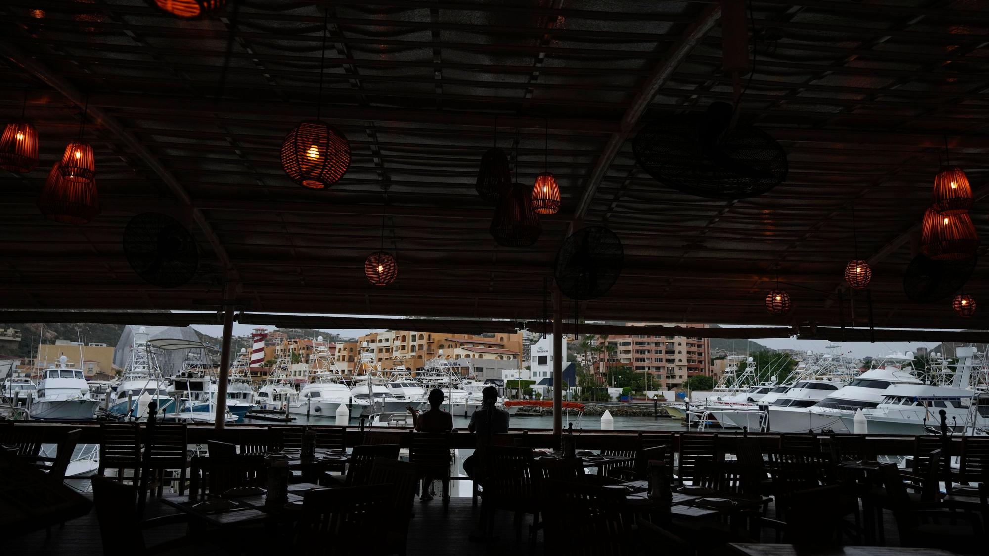 Ein Touristenpaar nimmt einen Drink in einer noch geöffneten Bar am Hafen von Cabo San Lucas.