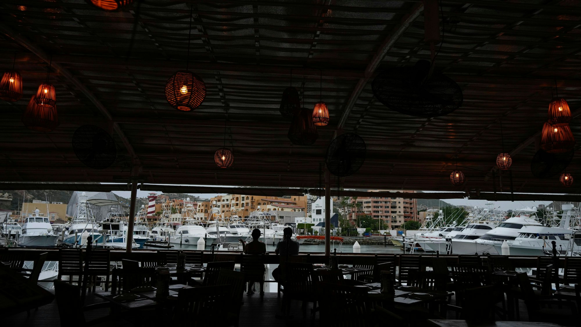 Ein Touristenpaar nimmt einen Drink in einer noch geöffneten Bar am Hafen von Cabo San Lucas.
